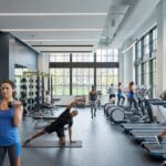 Personnes faisant de l'exercice dans une salle de sport lumineuse et moderne avec des équipements de musculation.
