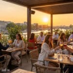 Des clients profitent d'un verre au coucher du soleil sur une terrasse élégante avec vue sur la Seine.