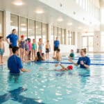 Enfants apprenant à nager avec des instructeurs dans une piscine intérieure lumineuse à Boulogne-Billancourt.
